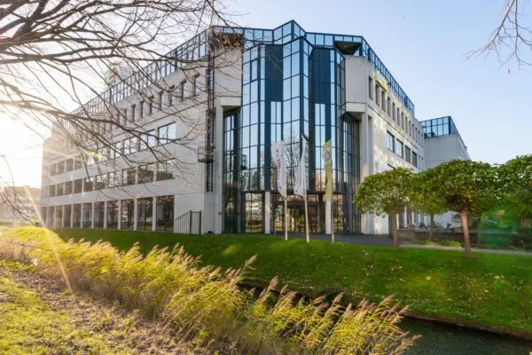 Modern kantoorgebouw aan de De Bruyn Kopsstraat met grote ramen en vlaggen bij de entree.